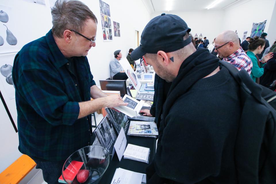 Publisher explaining a book to a visitor